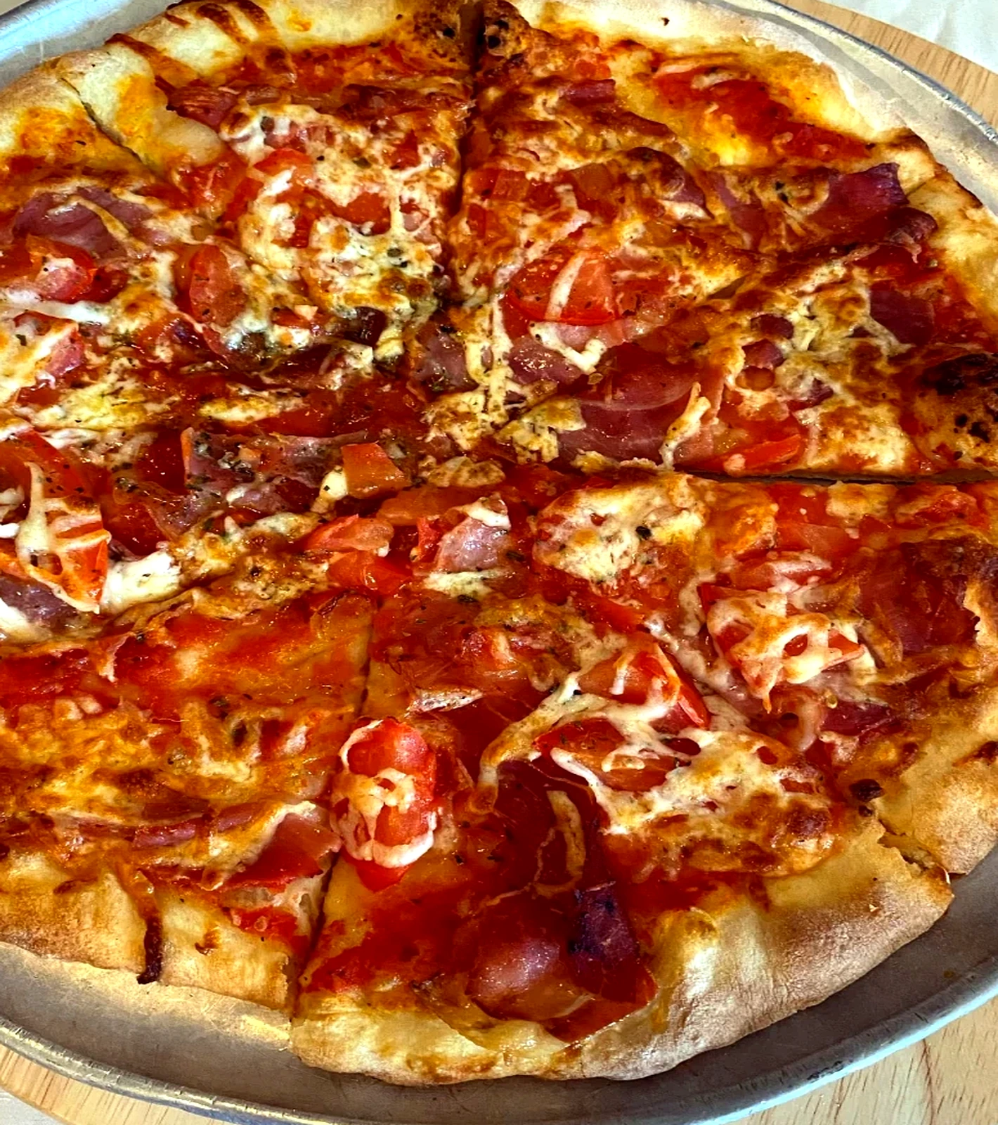 Stone-baked pizza with tomato, cheese and cured meat toppings
